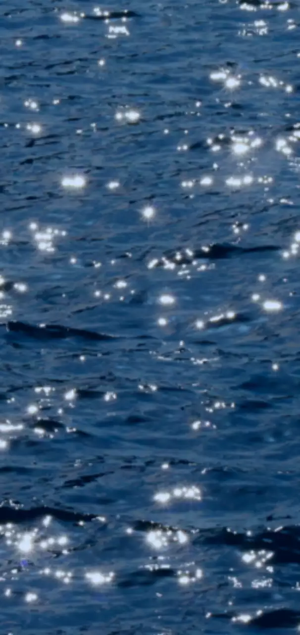 A photo of waves sparkling in blue light