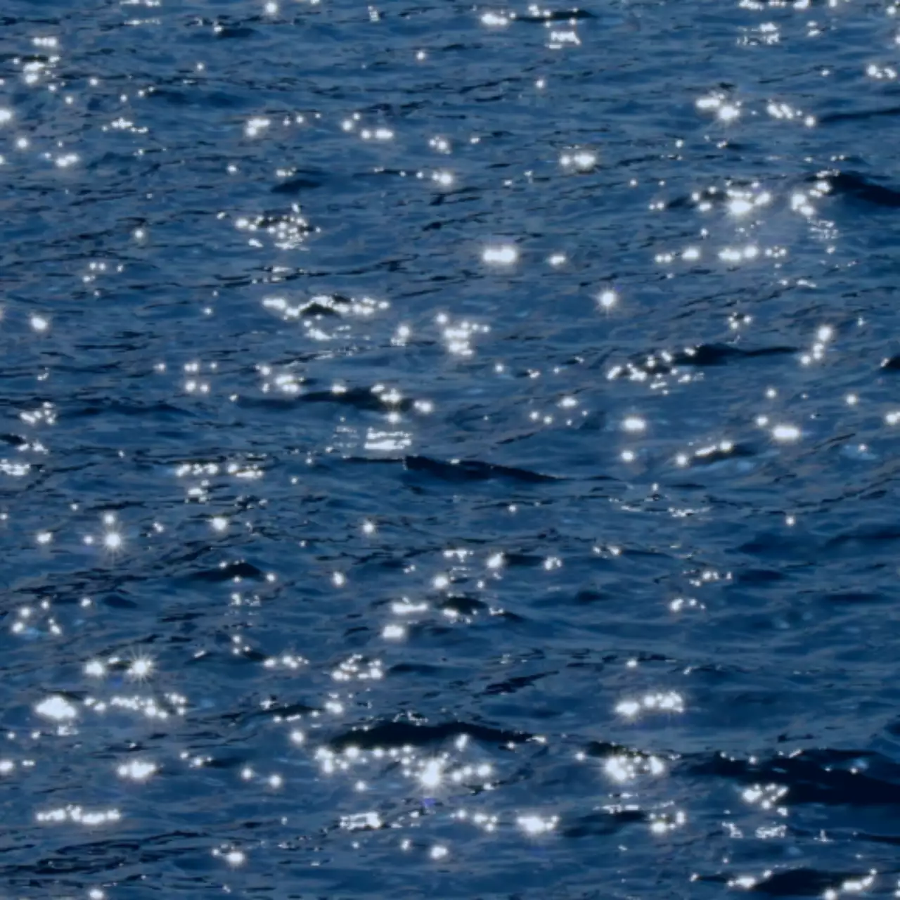 Foto ombak yang berkilauan dalam cahaya biru