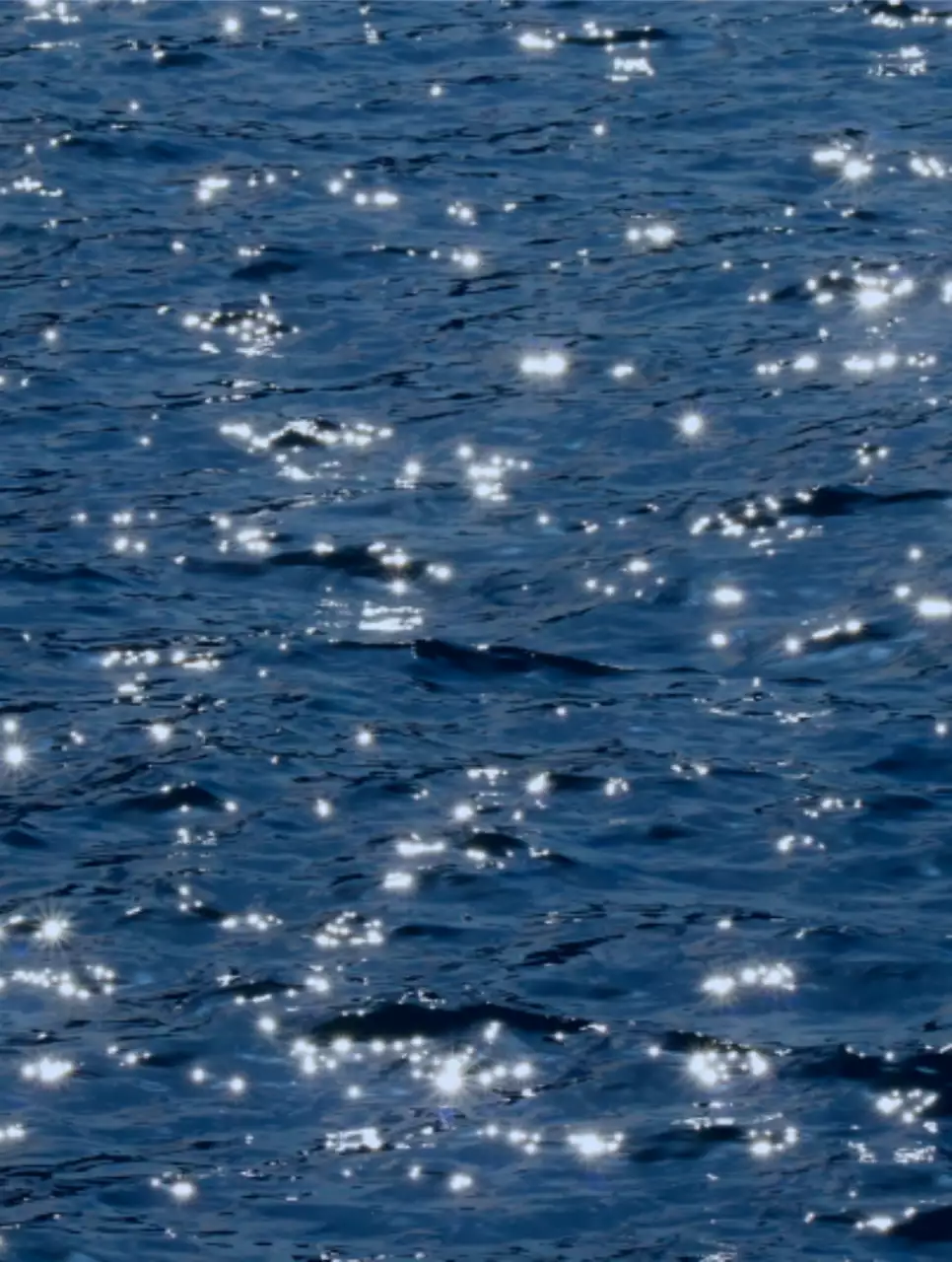 A photo of waves sparkling in blue light